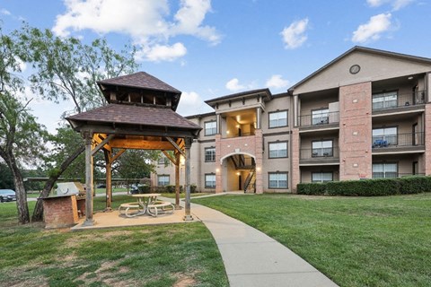 a pavilion with a picnic table in front of an apartment building