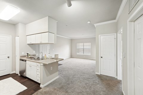 an empty kitchen and living room with white cabinets