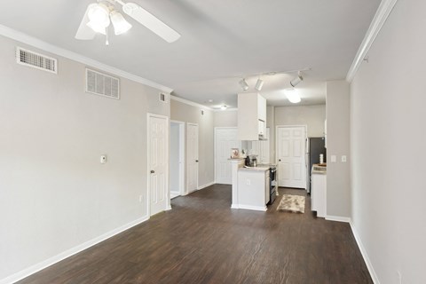 an empty living room and kitchen with white walls and wood flooring