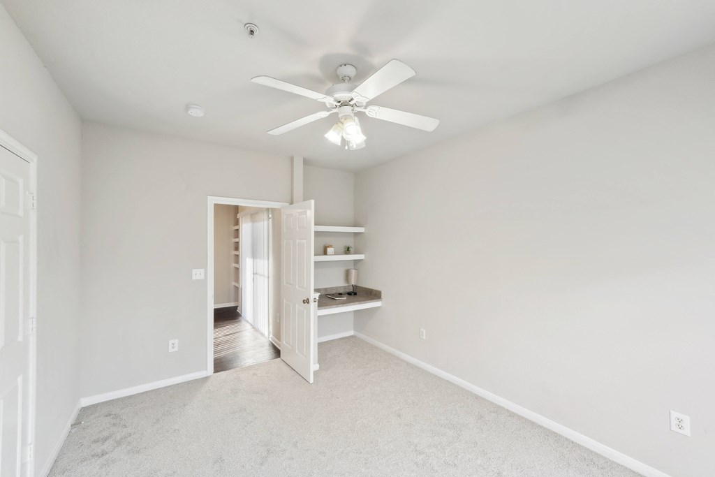 an empty bedroom with a ceiling fan and a closet