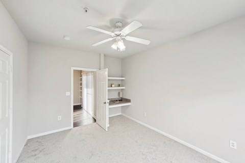 an empty bedroom with a ceiling fan and a closet