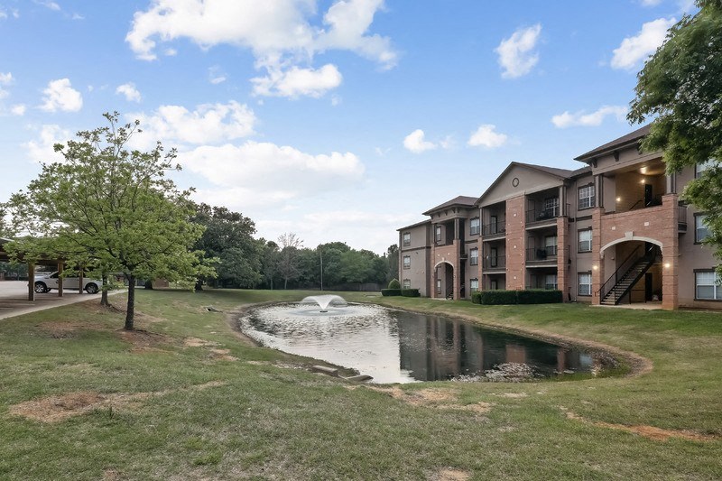 an apartment building with a small pond in the middle