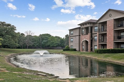 a pond with a fountain in front of an apartment building