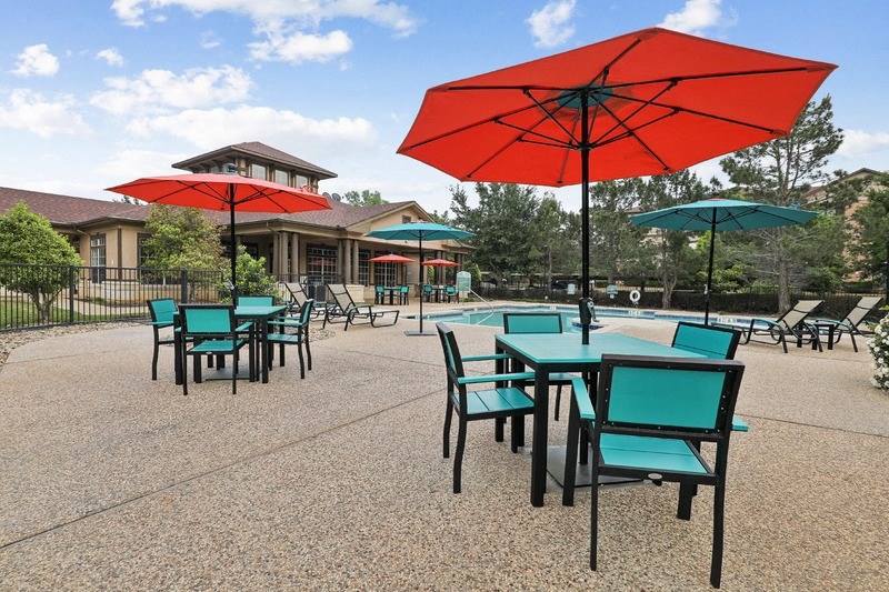 a patio with tables with umbrellas and chairs