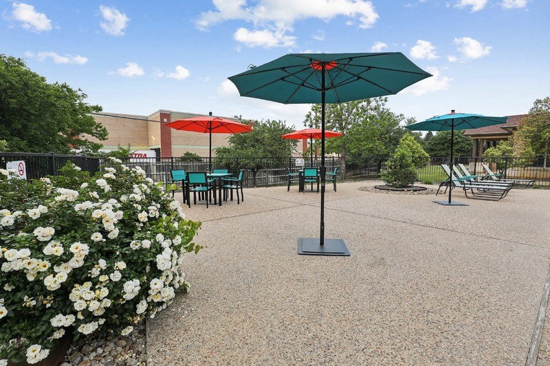 a patio with umbrellas and tables with chairs and flowers