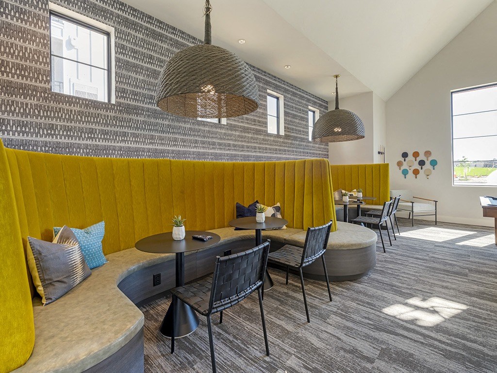 a lounge area with tables and chairs and two pendant lights