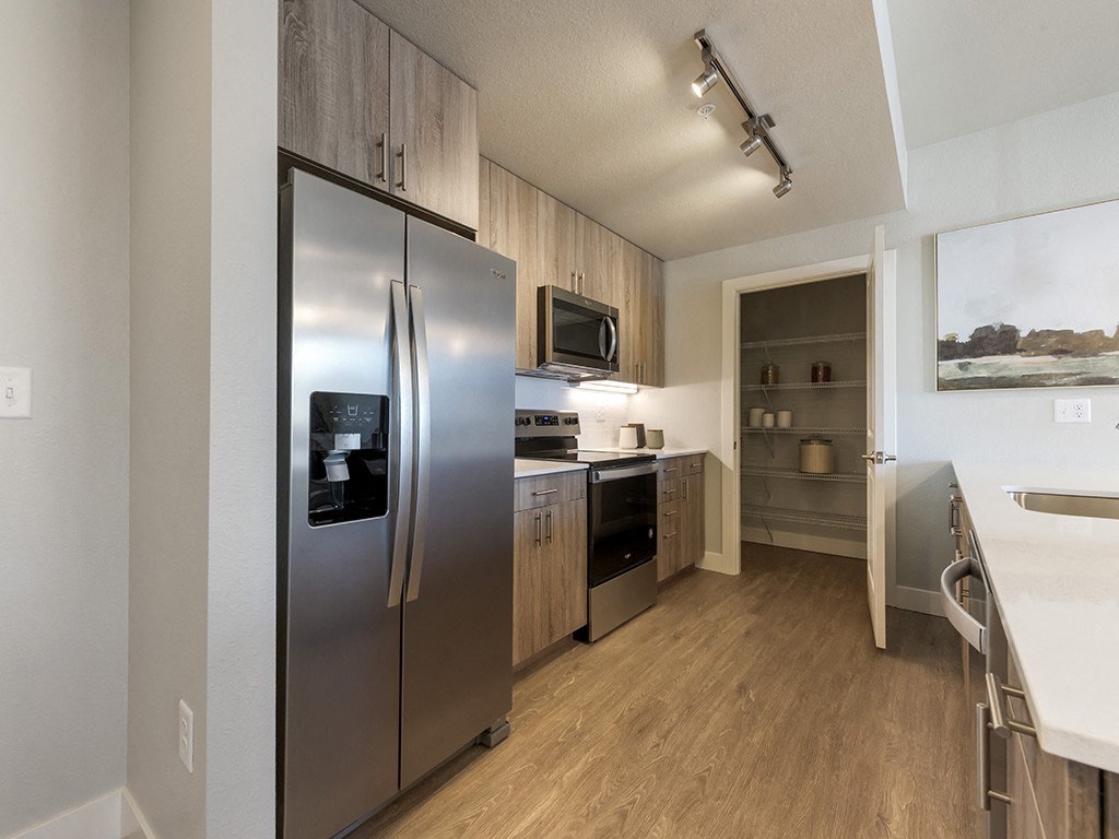A modern kitchen with a stainless steel refrigerator and wooden cabinets.