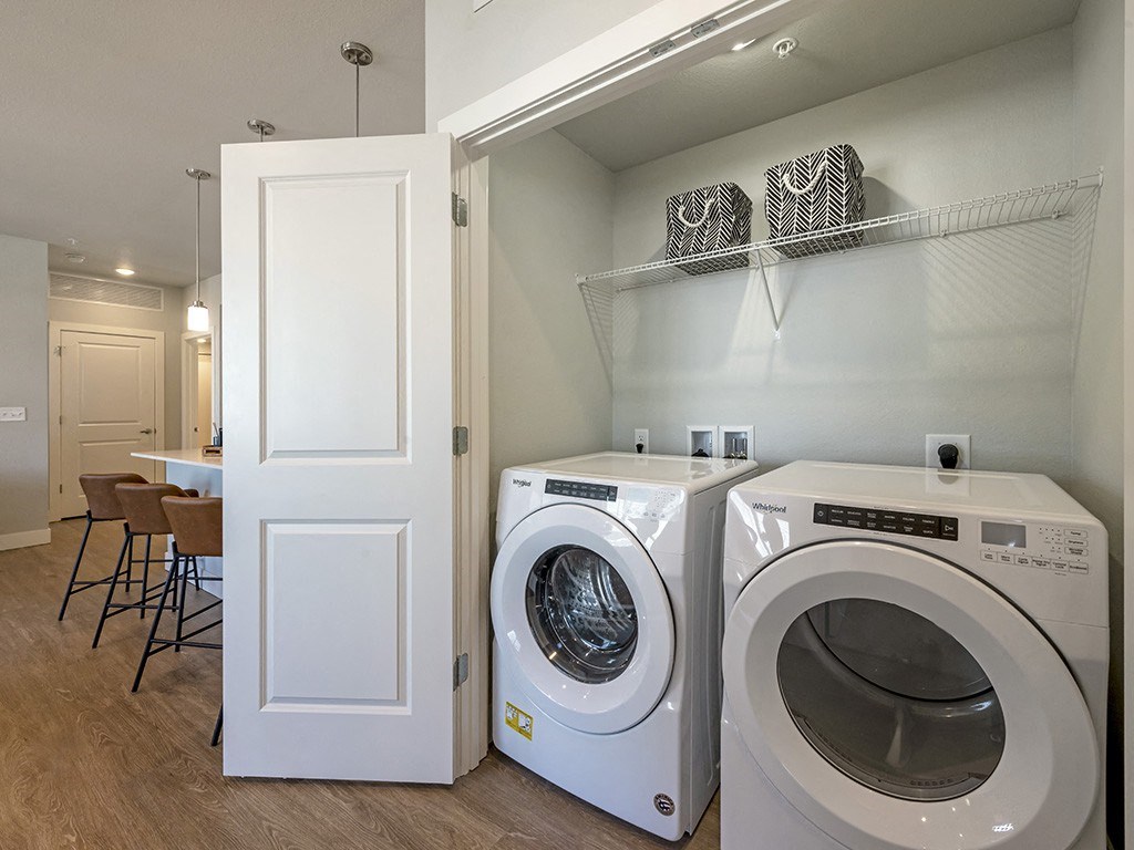 A white door is open to a laundry room with two washing machines.