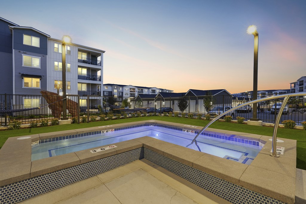 a swimming pool at dusk with an apartment building in the background
