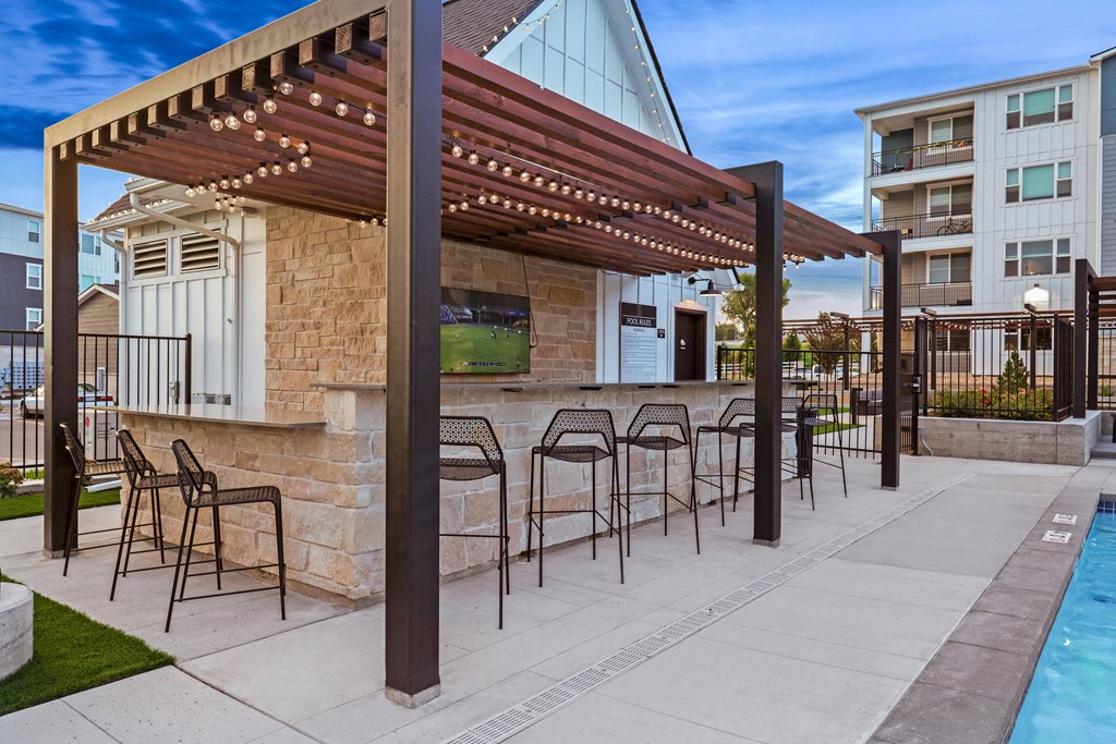 a patio with chairs and a bar next to a pool