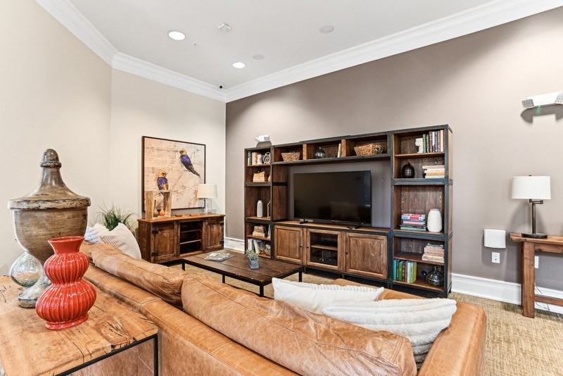 A living room with a brown leather couch and a wooden bookshelf.