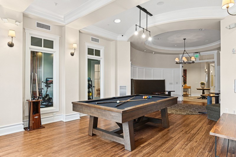 A pool table is in the middle of a room with wood floors and white walls.