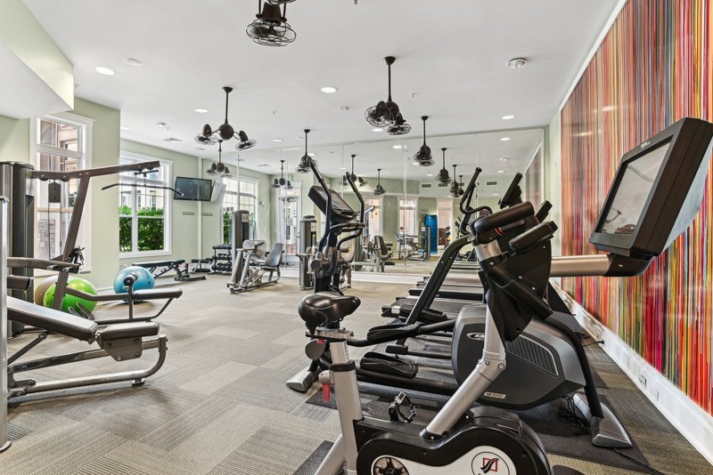 A gym with a variety of exercise equipment including treadmills, stationary bikes, and weight machines.