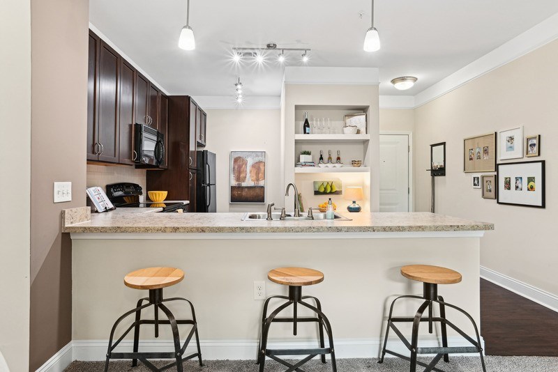 A kitchen with a bar area featuring a granite countertop and stools.