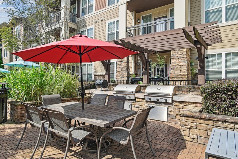 A patio with a table and chairs under a red umbrella.