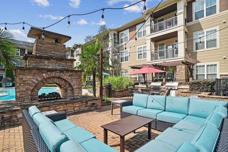 A patio with a brick fireplace and a blue couch.