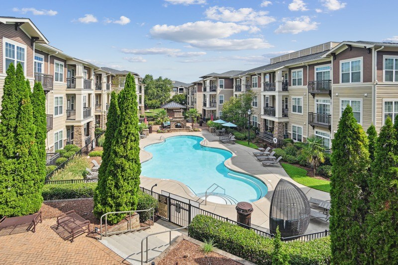 A swimming pool surrounded by apartment buildings and trees.