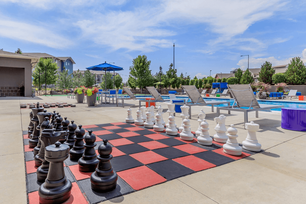 A giant chess set is set up on a checkered board in a courtyard.
