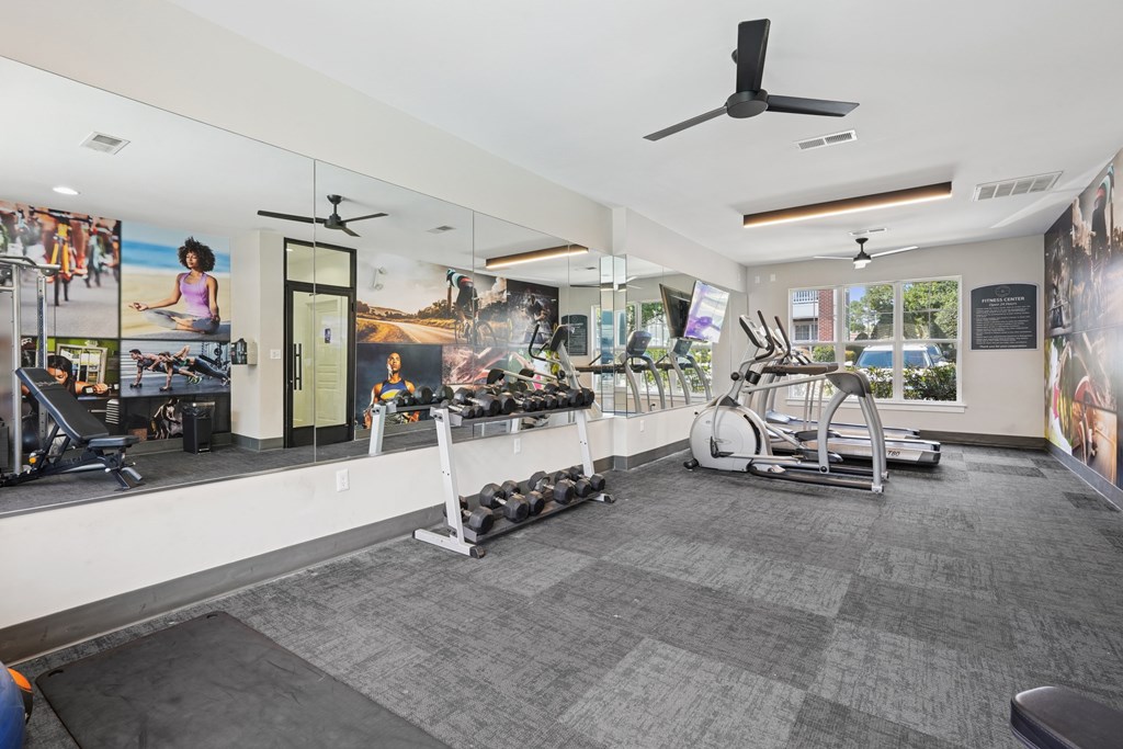 A gym with a variety of equipment including treadmills, weights, and exercise machines.