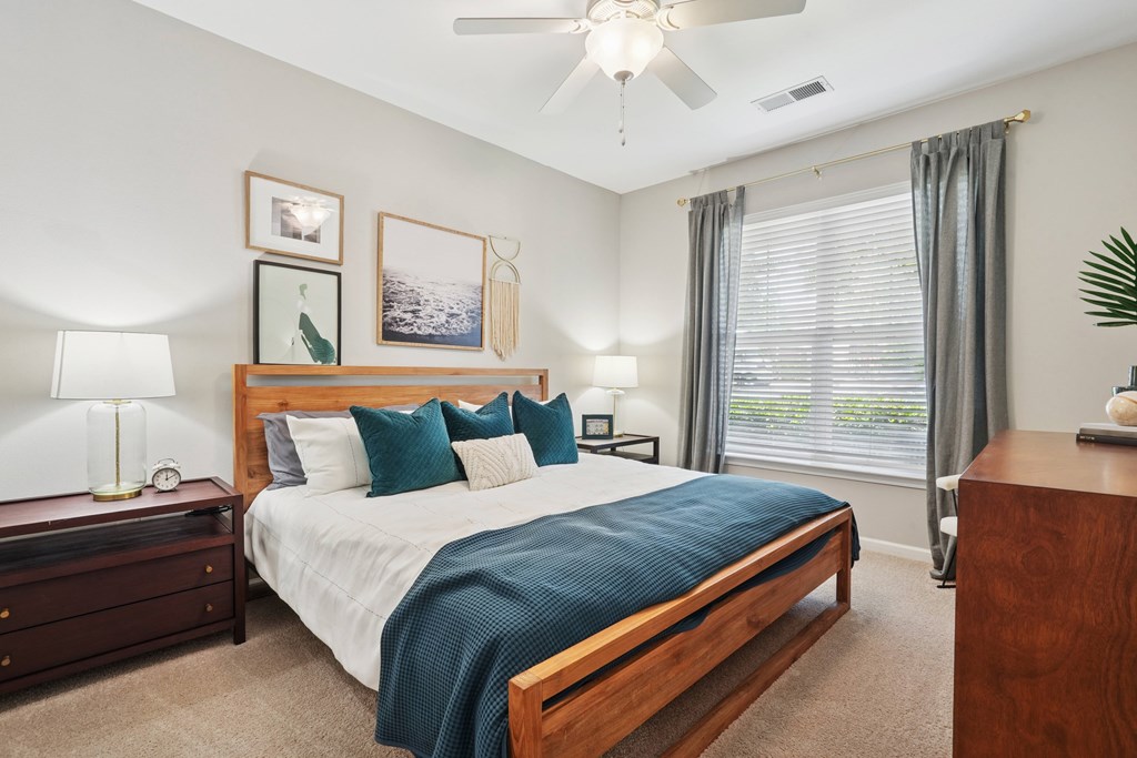 A bedroom with a bed, nightstand, and a ceiling fan.
