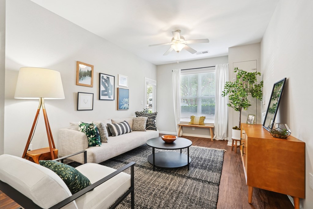 A living room with a white couch, a wooden floor, and a ceiling fan.