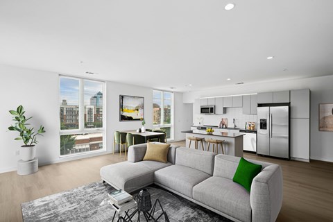 a living room with a gray couch and a kitchen with stainless steel appliances