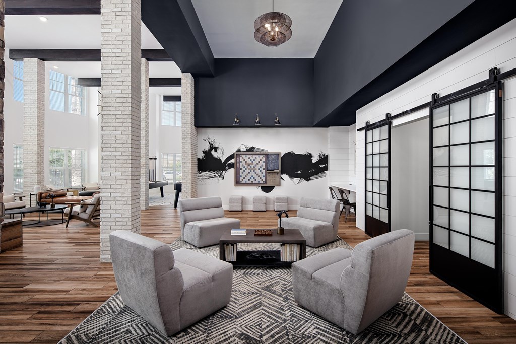 A modern living room with a grey sofa and a black and white rug.
