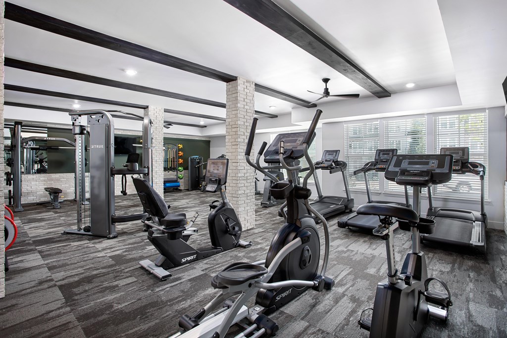 A gym with a variety of equipment including treadmills, stationary bikes, and weight machines.