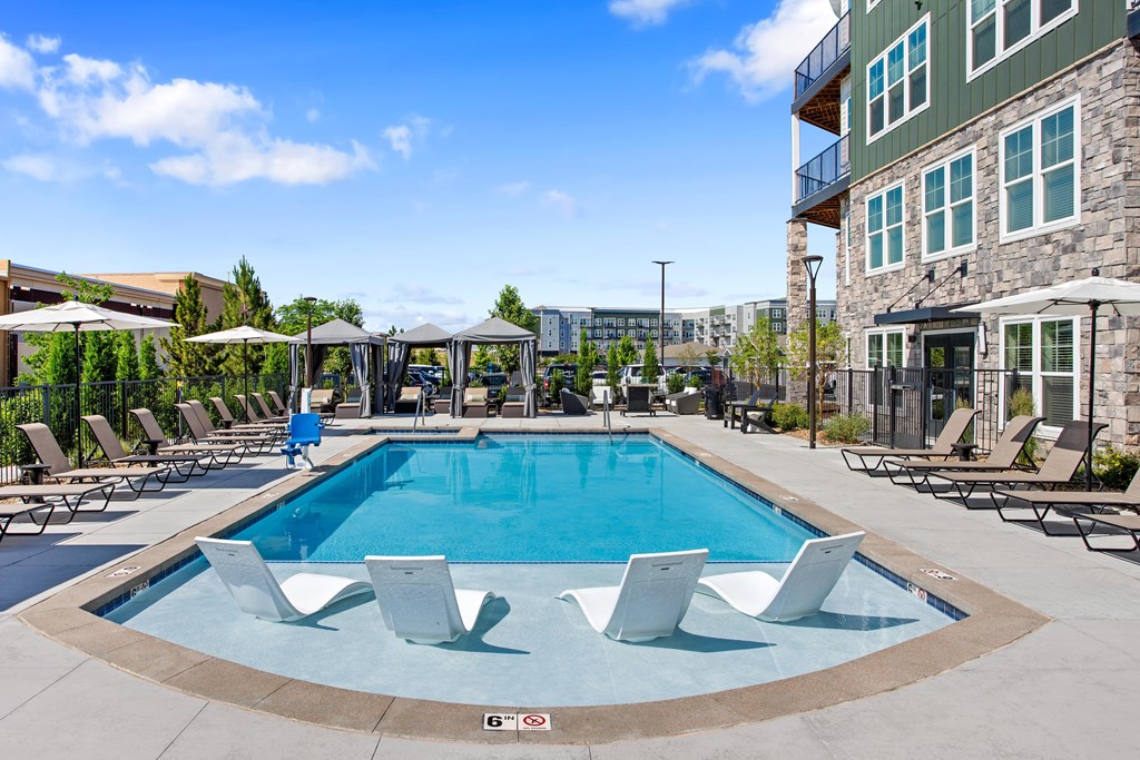 A large swimming pool surrounded by lounge chairs and umbrellas.