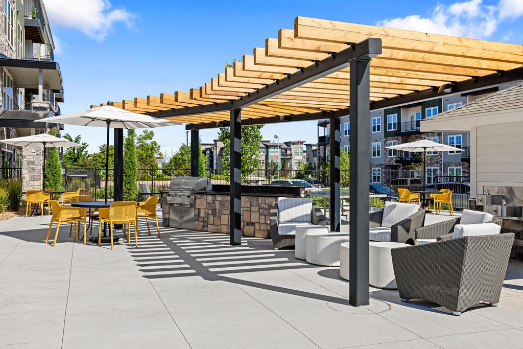 A patio with a table and chairs under a wooden pergola.