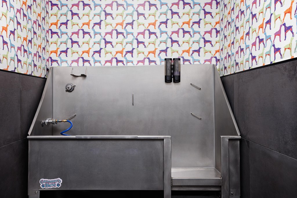 A large stainless steel sink in a room with a colorful patterned wallpaper.