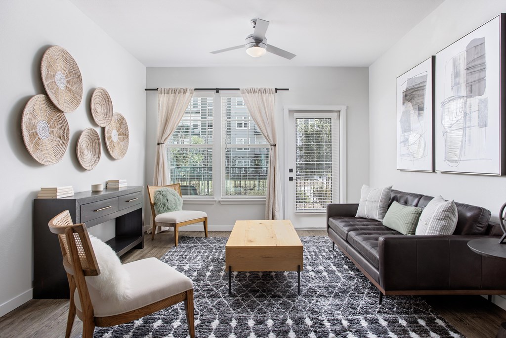 A living room with a brown leather couch, a wooden chair, and a coffee table.