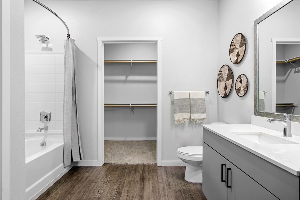A white bathroom with wood flooring and a white toilet.