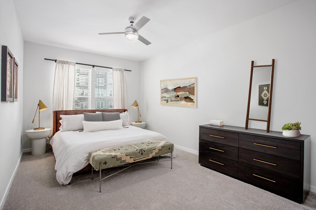 A bedroom with a bed, dresser, and a painting on the wall.
