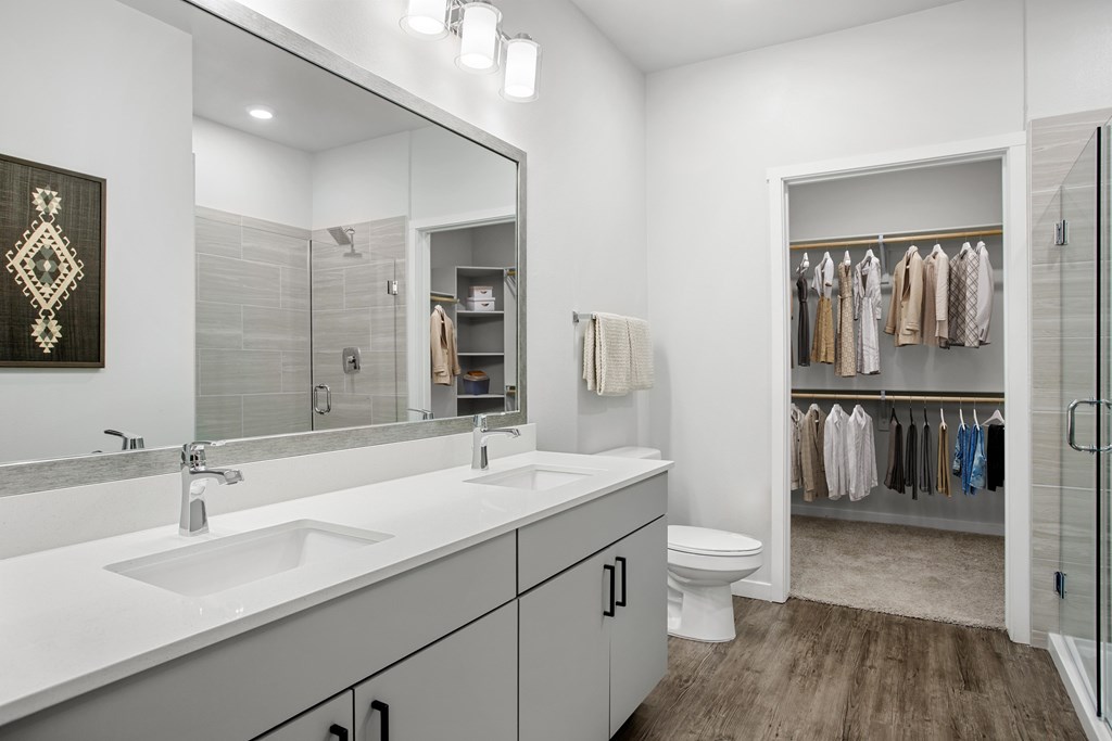 A bathroom with a white counter top and a mirror.