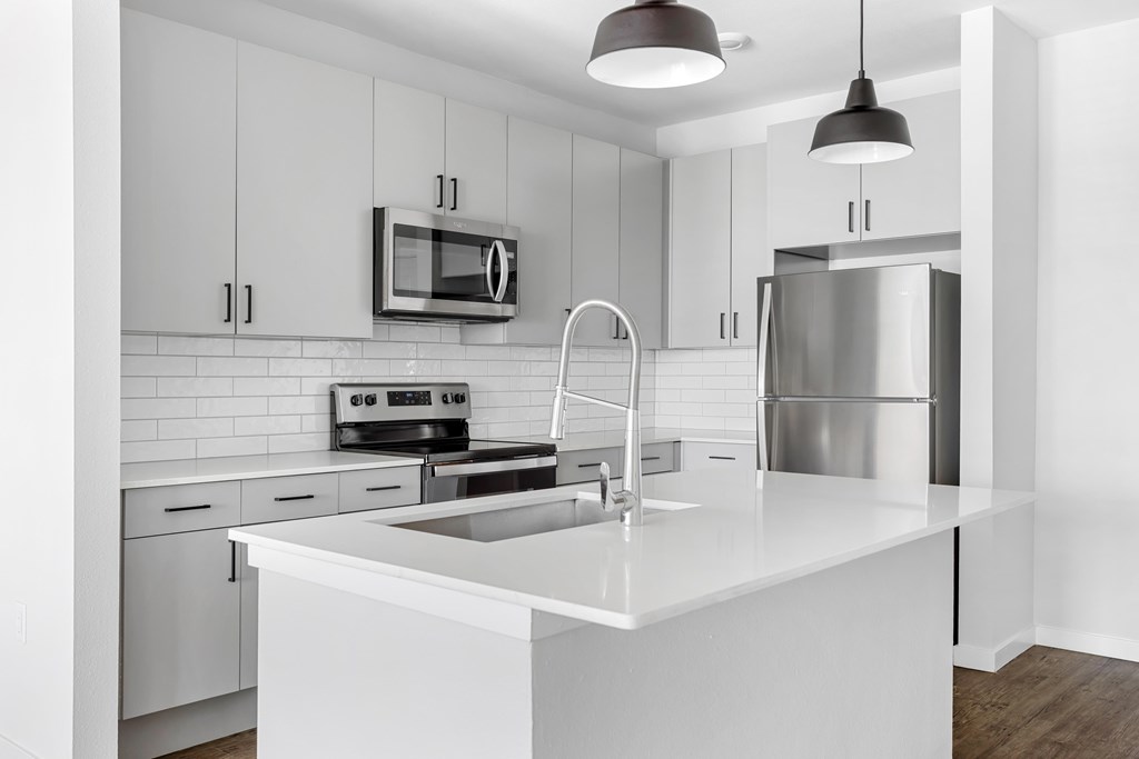 A modern kitchen with white cabinets and a stainless steel refrigerator.