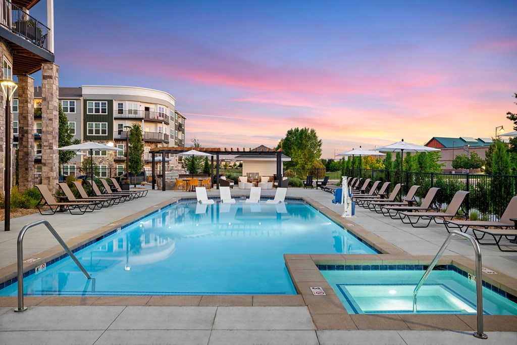 A large outdoor swimming pool with a fountain in the middle surrounded by lounge chairs.