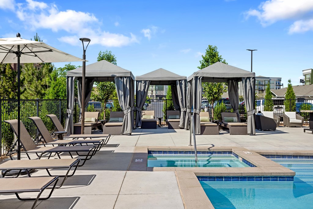 A pool area with sun loungers and umbrellas.