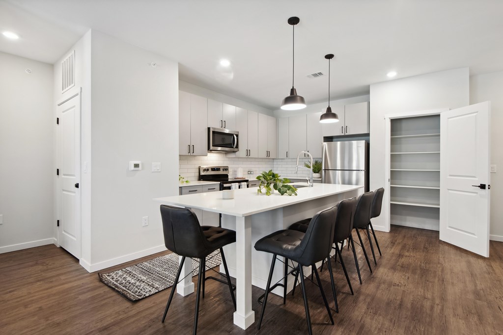 A modern kitchen with a white table and black chairs.