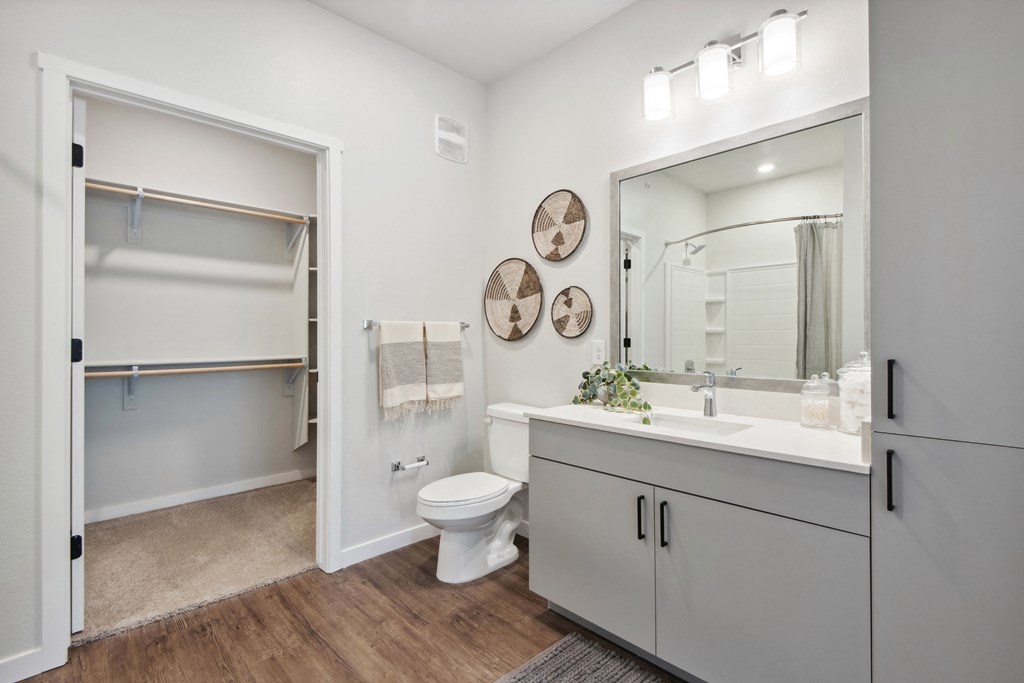 a white bathroom with a large mirror and a white toilet