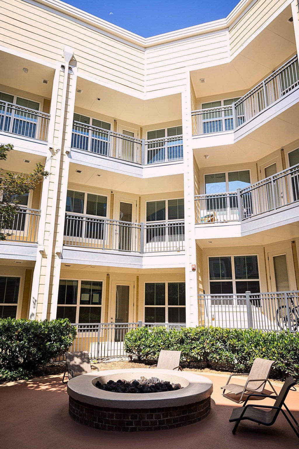 A white building with balconies and a fire pit in front.