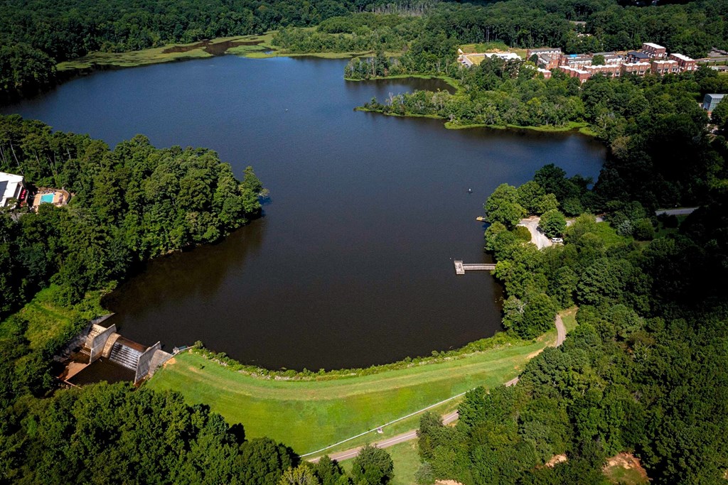 A large lake surrounded by green trees and a building on the left side.
