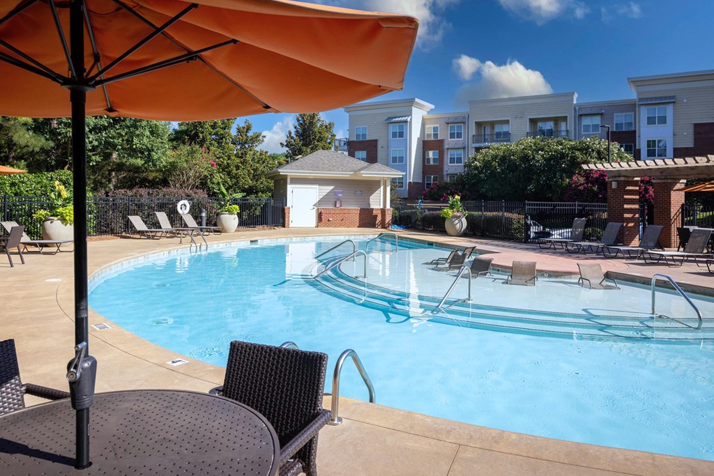 A pool with a table and chairs and an umbrella.