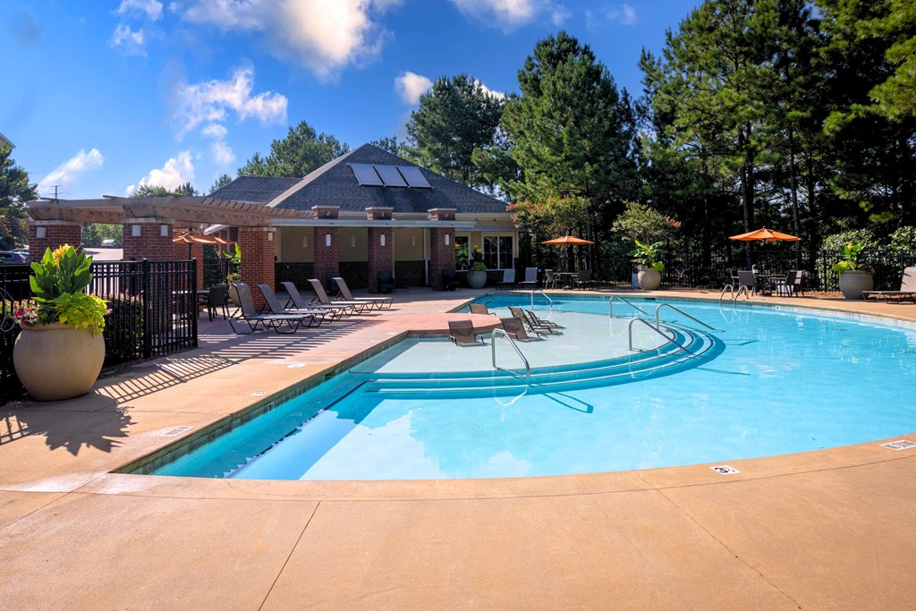 A swimming pool with a sun lounger and a building in the background.