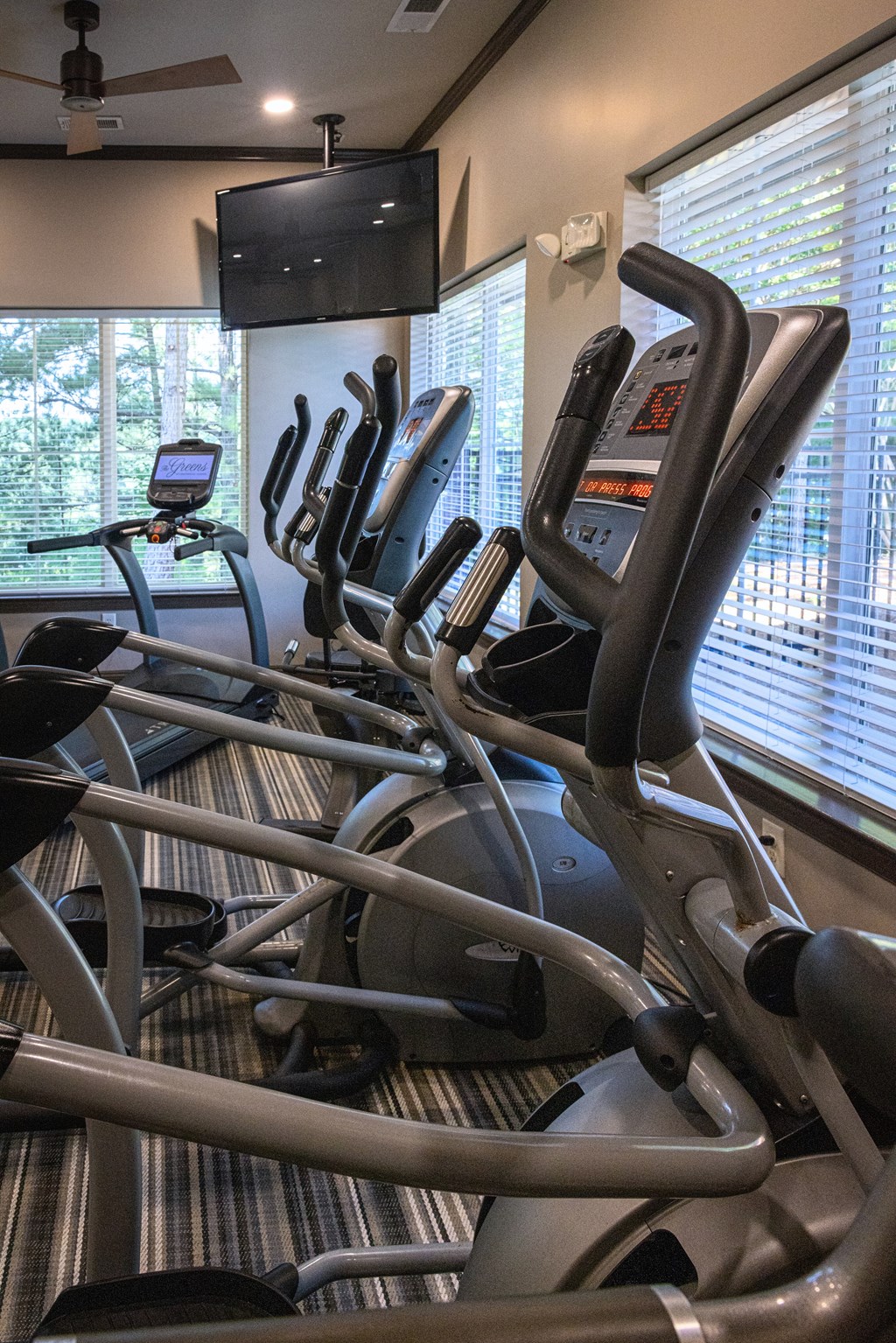 A gym with treadmills and a television mounted on the wall.