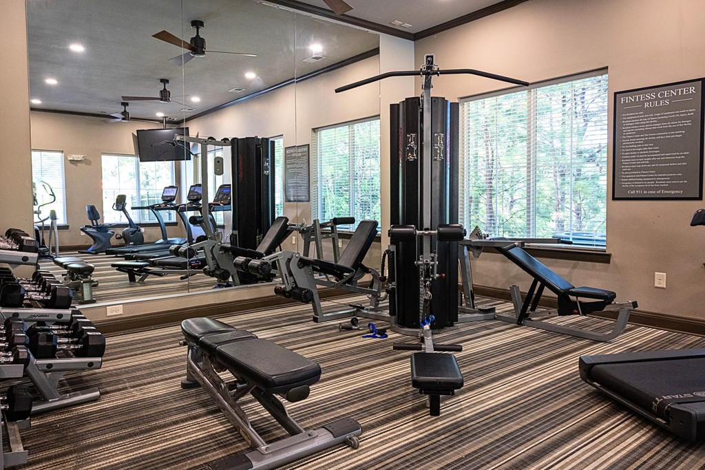 A gym with a variety of equipment including a squat rack, bench, and weights.