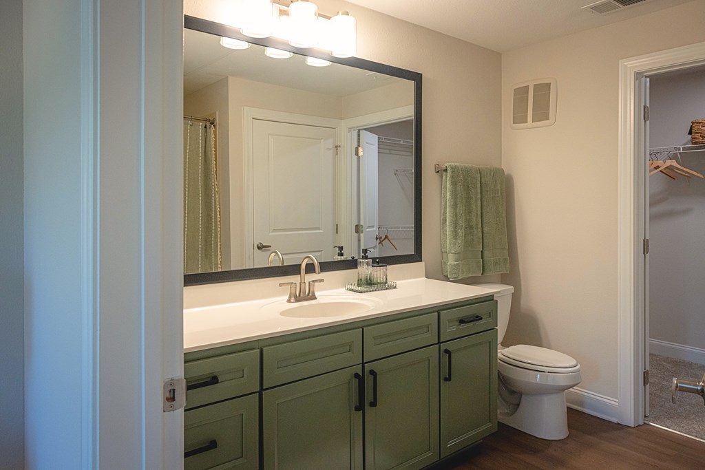 A bathroom with green cabinets and a white toilet.