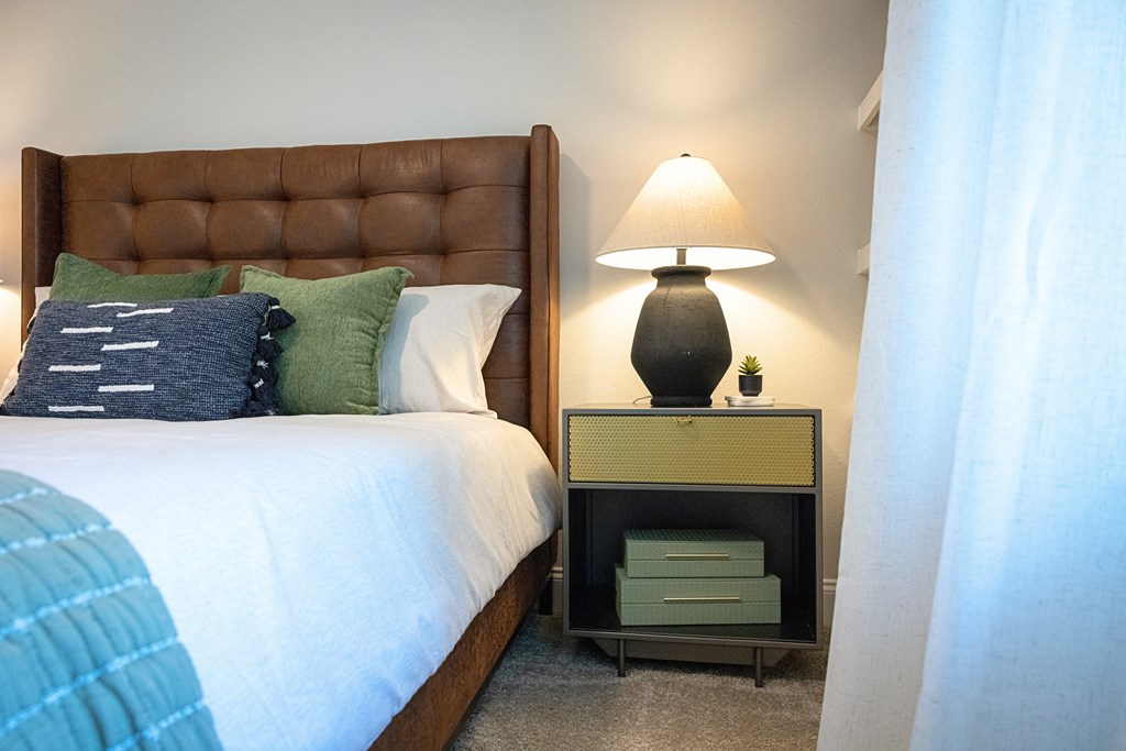 A bedroom with a brown headboard and a white bedspread.