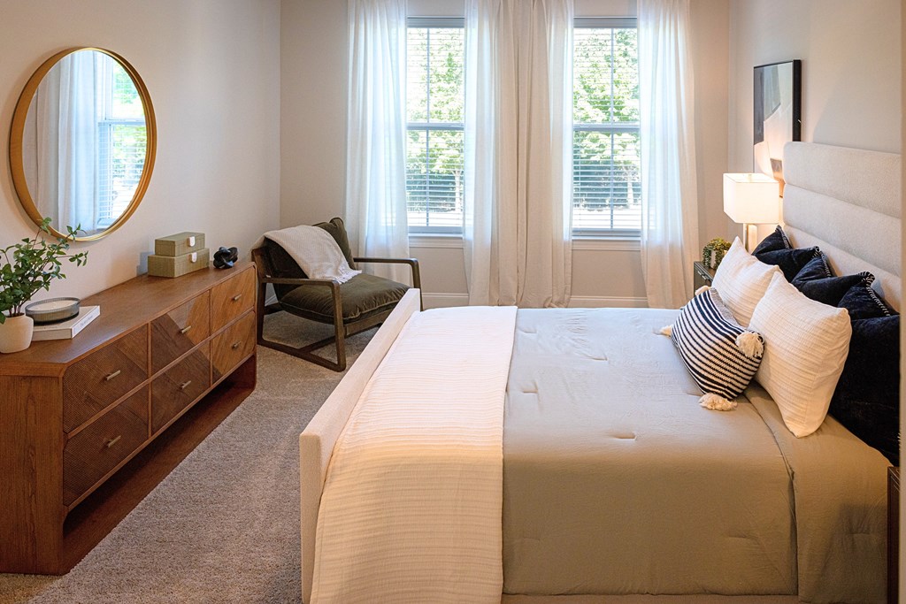 A bedroom with a large bed and a chair by the window.