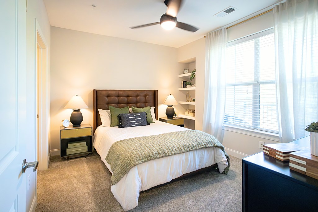 A bedroom with a bed, nightstands, and a ceiling fan.